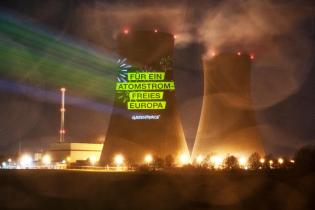 Mit der Projektion von Feuerwerkskörpern und dem Slogan "Für ein atomfreies Europa!"  demonstrieren Greenpeace-Aktivist:innen nachts auf einen Kühlturm des Atomkraftwerks Grohnde.