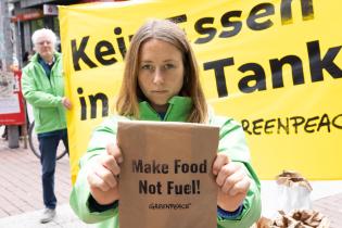 Aktion gegen Essen im Tank in Hamburg: Aktivistin hält Papiertüte mit der Aufschrift "Make Food Not Fuel!"