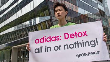 08. Mai 2014: Greenpeace-Aktivistin mit Protestbanner vor dem Adidas-Laden in Peking. Der Markenhersteller lässt fasst alle seine Artikel unter Einsatz giftiger Chemikalien in China fertigen