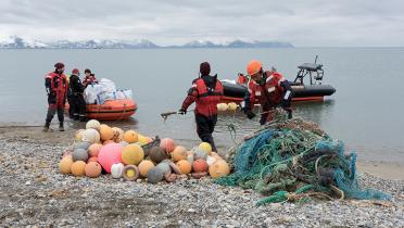 Greenpeace-Aktivisten mit Plastikmüll und Schlauchboot am Strand von Spitzbergen