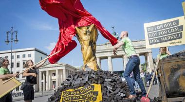 Greenpeace-Aktivisten enthüllen einen mit Kohle verschmutzen WM-Pokal vor dem Berliner Tor