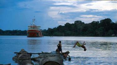 Kinder spielen im Juru River in Brasilien, im Hintergrund "Amazon Guardian" im Mai 2000