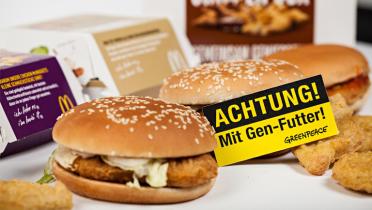 Burger von McDonald's versehen mit einem Warnschild, das auf Gentechnik hinweist