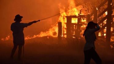 zwei Personen versuchen ein loderndes Feuer in Australien zu löschen