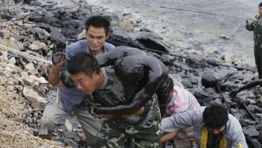 Helfer retten einen der beiden Feuerwehrmänner aus dem Öl im Juli 2010