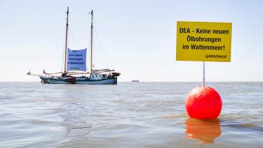 Boje mit schwimmenden Banner gegen Ölbohrungen, Beluga im Hintergrund