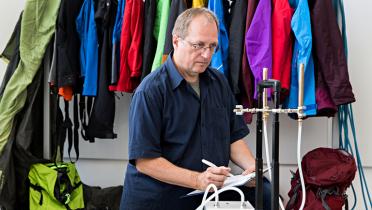 Greenpeace-Chemieexperte Manfred Santen bei Datennahme Raumluftmessung, dahinter Outdoorkleidung