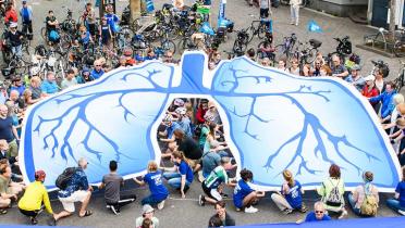 Aktivisten legen ein Banner mit aufgedruckter Lunge auf einen Platz