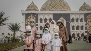 Familie mit Atemmasken vor Moschee