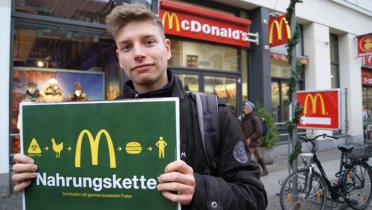 Ein Passant lässt ein Foto von sich mit einem Motiv gegen den Einsatz genamipulierten Futters bei McDonalds fotografieren