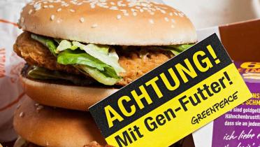 Chickenburger von McDonald's mit Greenpeace-Schild: "Achtung! Mit Gen-Futter!"