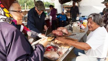 Cree-Mitglieder bereiten an einem Tisch Fleisch zu. 