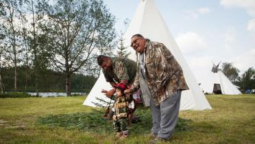 Zwei Cree führen ihren Nachwuchs aus einem Zeit zu einem kleinen Baum direkt davor. 