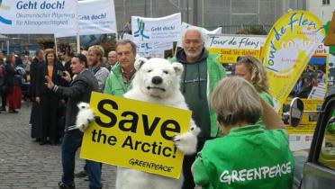 Am Greenpeace-Stand auf dem Markt der Möglichkeiten hält ein als Eisbär Verkleideter ein "Save The Arctic"-Schild hoch.