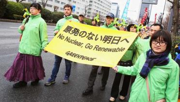 Auf einer Straße in Tokio halten Greenpeace-Aktivisten ein Transparent mit der Aufschrift "Keine Atomkraft - Erneuerbare"