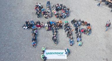 Greenpeace-Aktivisten formen auf dem Marburger Marktplatz ein menschliches Banner: Kein TTIP