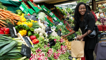 Frau an einem Gemüsestand auf dem Markt