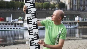 Greenpeace-Aktivist hält große Pegelmesslatte hoch.