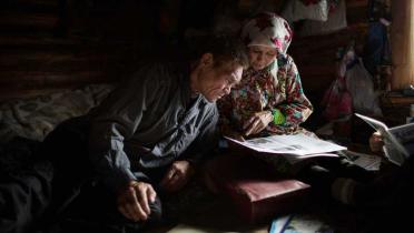 Sergey Kechimov und seine Frau Capitalina in ihrem Haus. Sie beugen sich über eine Zeitung.