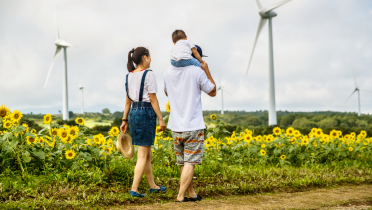 Eine Familie spaziert vor einem Windpark entlang