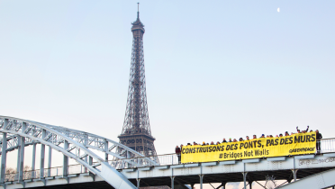 Greenpeace-Aktivisten vor dem Eiffelturm mit einem Banner: "Brücken bauen statt Mauern"