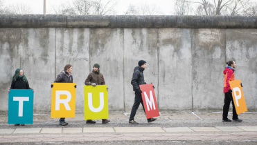 Vor dem Berliner Mauerdenkmal formieren sich Greenpeace-Aktivisten mit Schrifttafeln, um "Brücken statt Mauern" zu fordern.