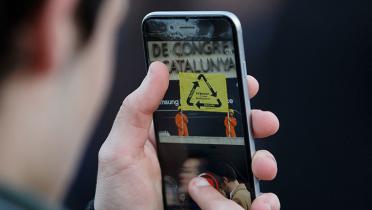 Blick aufs Display eines Smartphones: Im Sucher die Protestaktion mit Aktivisten und Banner