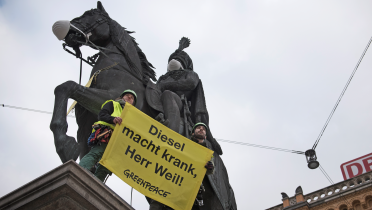 Greenpeace-Aktivisten in Hannover setzen dem Ernst-August-Denkmal eine Atemschutzmaske auf