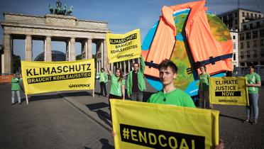 Aktivisten in Berlin vorm Brandenburger Tor, sie zeigen einen Globus mit angelegter Rettungsweste