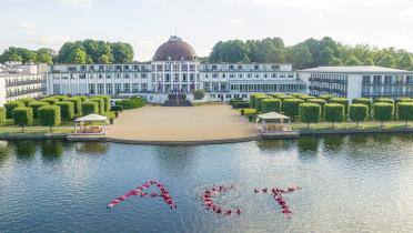 Greenpeace-Aktivisten in Schwimmanzügen bilden im Hotelsee das Wort "Act"