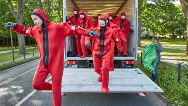 Greenpeace-Aktivisten in Überlebensanzügen springen von der Ladefläche eines Lastwagens