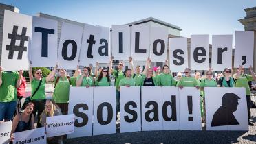 Flashmob in Berlin, Aktivisten mit Schildern "Total Loser, so sad"