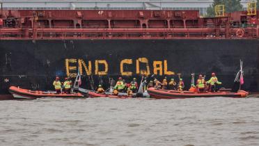 In großen Buchstaben haben Greenpeace-Aktivisten in Schlauchtbooten "End Coal" an die Bordwand des Frachters "Golden Opportunity" geschrieben