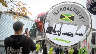 Rundbanner "Illegalize it" mit fotografierendem Aktivisten