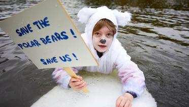 Kind im Eisbärkostüm im Bonner Rheinauensee, Banner "Save The Polar Bears!"