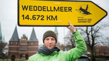 Aktivist mit Wegweiser vorm Holstentor in Lübeck