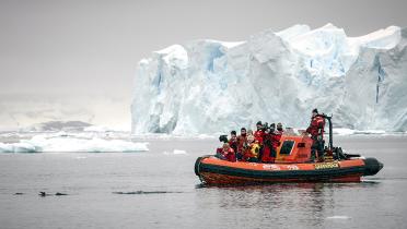 Greenpeace-Mannschaft in Schlauchboot vor Eisberg