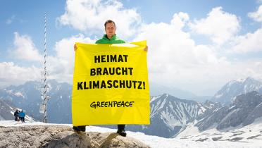 Aktivist mit Handbanner "Heimat braucht Klimaschutz" auf der Zugspitze