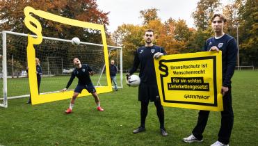 Fußballspieler protestieren vor Fußballtor für ein Lieferkettengesetz