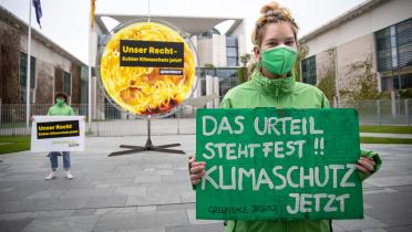 Aktivistin mit Handbanner "Das Urteil steht fest - Klimaschutz jetzt!" vorm Bundeskanzleramt