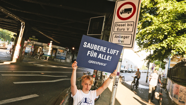 Vor einem Diesel-Fahrvertotsschild an der Stresemannstraße in Hamburg demonstriert eine Greenpeace-Aktivistin für "Saubere Luft für alle".