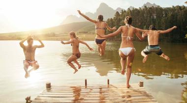 Eine Gruppe junger Menschen springt in einen See