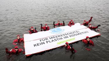 Aktivisten mit Schwimmbanner gegen Mikroplastik
