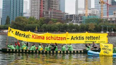Greenpeace Aktivisten in einem Boot auf dem Frankfurter Main halten ein Banner: "Frau Merkel: Klima schützen - Arktis retten!".