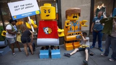 Menschen in Legokostümen protestieren gemeinsam mit weiteren Menschen vor dem Legogeschäft in New York