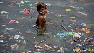 In der Bucht von Manila, Philippinen, badet ein Junge inmitten von Müll.