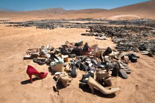 Müll aus Schuhen und Klamotten liegen in der Wüste rum