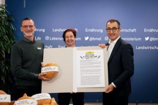 Kathrin Schroeder (Misereor) und Matthias Lambrecht (Greenpeace) über die Petition "Kein Essen in Tank und Trog" zusammen mit einem Brot an Landwirtschaftsminister Cem Özdemir