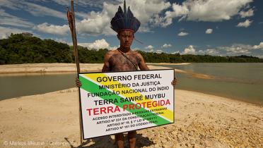 Junger Munduruku mit Demarkierungsschild für seine Heimat.