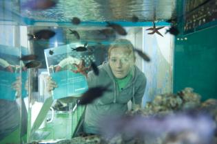 Eine Greenpeace-Ehrenamtliche hinter einem Aquarium des Ozeaneums in Stralsund.